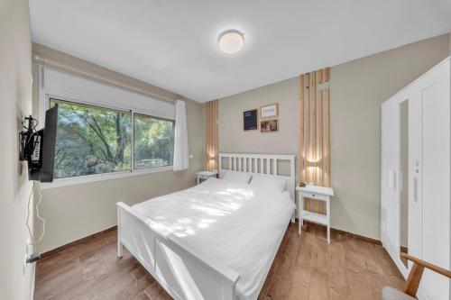 a bedroom with a white bed and a window at Engel apartments -אירוח למטיילים בגליל עליון in Tsiv'on