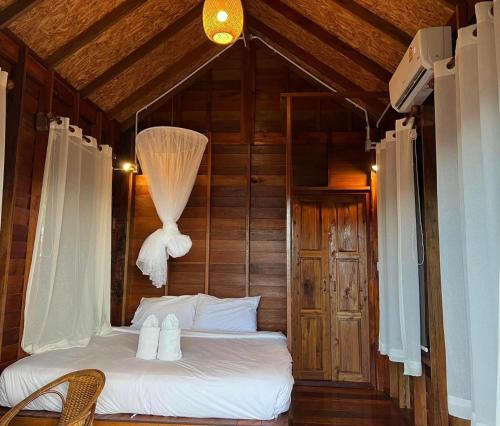 a bedroom with a bed in a room with wooden walls at Thammachart The Nature in Ban Kai Noi