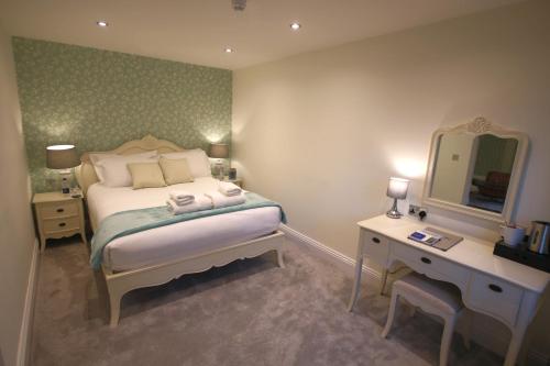 a bedroom with a bed and a desk and a mirror at The Malvern Hills Hotel in Great Malvern