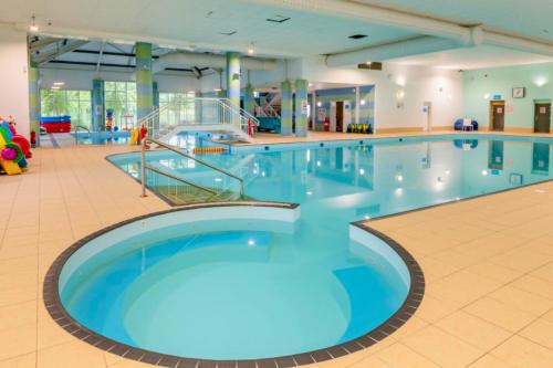 a large swimming pool with blue water in a building at Meadows 50 - Southview Holiday Park Skegness in Skegness