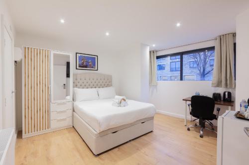 a white bedroom with a bed and a desk at Villas Apart Hotel in London