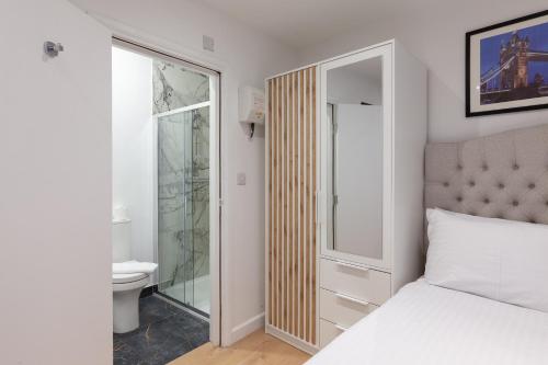 a bedroom with a bed and a bathroom with a toilet at Villas Apart Hotel in London