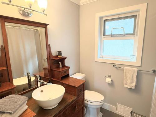 a bathroom with a sink and a toilet and a window at The Orange Door Bungalow- 2-BR w private yard, walkable to cafes & restaurants, 10 min to DT in Vancouver