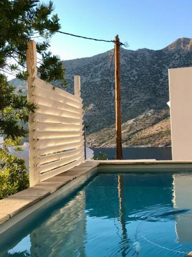 a swimming pool with a white fence and mountains in the background at Villa in Kamares, Sifnos in Kamares