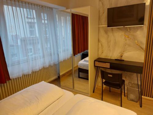 a bedroom with a bed and a desk with a mirror at Pension Alpha in Frankfurt
