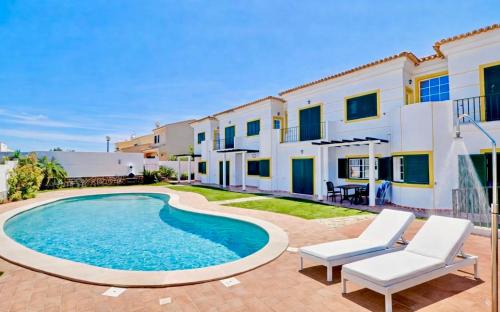 a villa with a swimming pool and two chairs at Casa Da Luz 18 - swimming pool and beach Town house in Luz