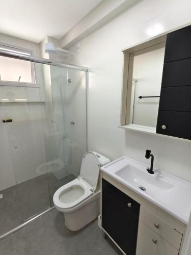 a bathroom with a toilet and a shower and a sink at bauer in Camboriú