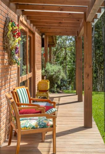 a porch with two chairs on a wooden deck at Casa Bosque Encantador in Rancho Queimado