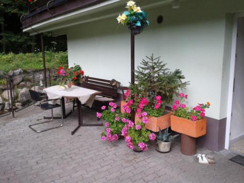 a patio with flowers and a table and a bench at Penzion Valovi in Merklín