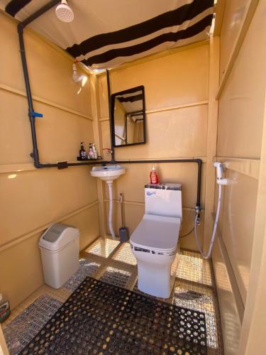 a small bathroom with a toilet and a sink at Desert Romance Retreat in Muntarib