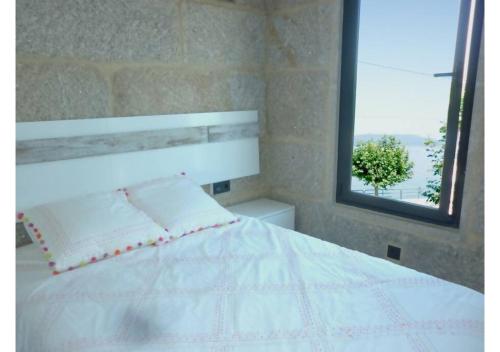 a bedroom with a white bed and a mirror at Piso con vistas a 30m playa ALOJAMIENTOS VACAY in Bueu