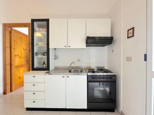 a white kitchen with a stove and a sink at Casa Mia - Baia Verde in Baia Verde