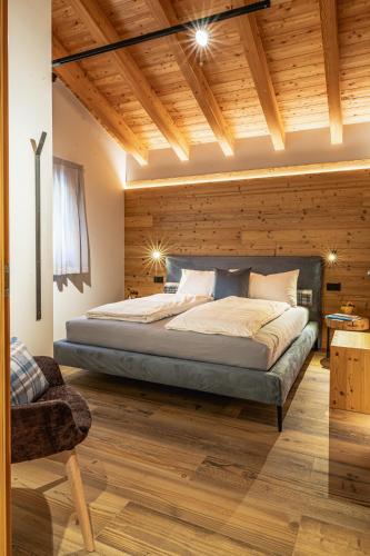 a bedroom with a large bed with a wooden wall at Baita Valon La Piciola in Stenico