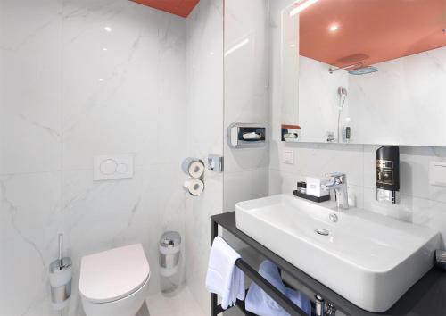 a white bathroom with a sink and a toilet at Mercure Frankfurt Offenbach in Offenbach