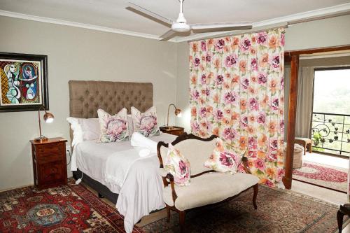 ein Schlafzimmer mit einem Bett, einem Stuhl und einem Fenster in der Unterkunft Cavalo Guesthouse & Equestrian Estate in Drummond