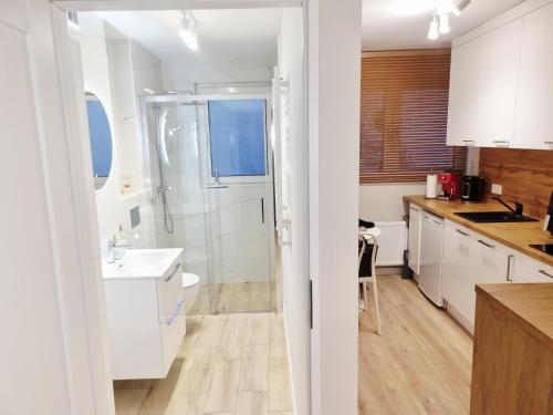 a white bathroom with a shower and a sink at Apartament Sobótka in Sobótka
