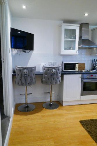 a kitchen with two bar stools in front of a counter at The Mews & Studio in Ivybridge