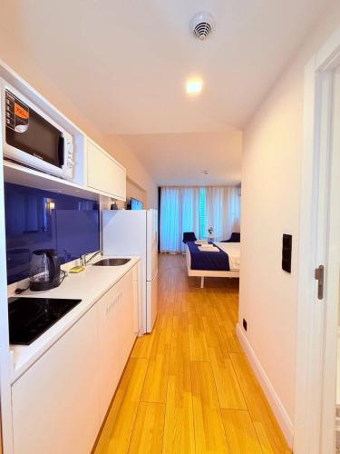 a kitchen with white cabinets and a room with a bed at ASKO aprtament beach batumi in Batumi