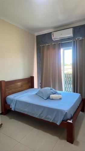 a bedroom with a blue bed with a window at Pousada Cabana in Avaré