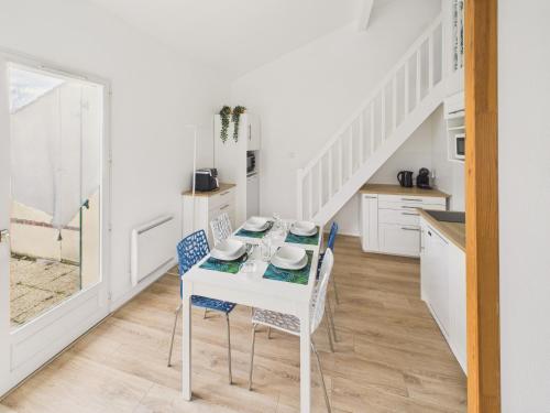 a white kitchen with a table and chairs and stairs at Maison proche Golf plage et piscine à Pornic in Pornic