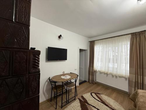 a room with a table and a tv on a wall at Casa Bunicii in Târgu Neamț