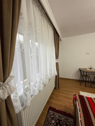 a room with a window with curtains and a table at Casa Bunicii in Târgu Neamț
