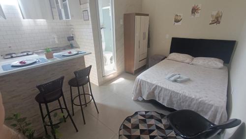 a bedroom with a bed and a kitchen with stools at Studio Home Residence in Jacareí