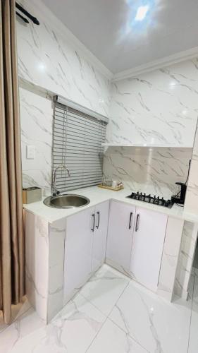 a kitchen with white marble walls and a sink at Mjee's Guest House in Ulundi