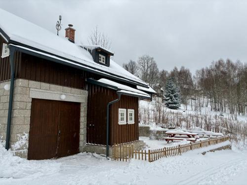 a wooden building with a garage in the snow at Chalupa Andělka in Josefŭv Dŭl