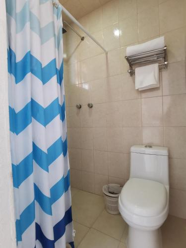 a bathroom with a toilet and a blue and white shower curtain at Villa platino in Pachuca de Soto