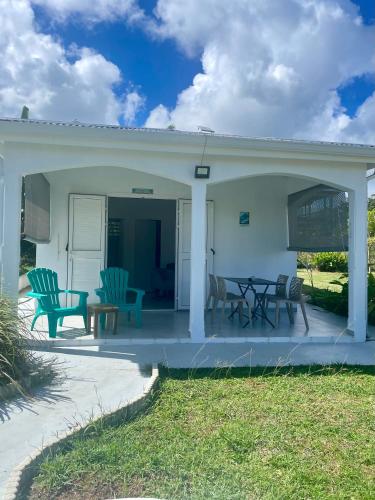a white house with a patio with chairs and a table at Mango-passion Le Domaine Mannou in Sainte-Rose