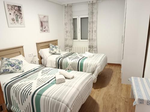two beds in a room with white walls at San Andres 14 in Teruel