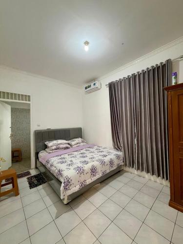 a bedroom with a bed and a window with curtains at Villa puncak 3 room in Cikundul