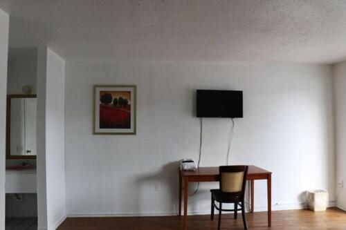 a desk with a chair and a television on a wall at Dunedin Cove Motel in Dunedin