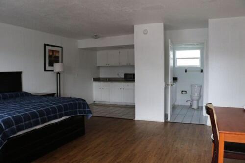 a bedroom with a bed and a desk and a kitchen at Dunedin Cove Motel in Dunedin
