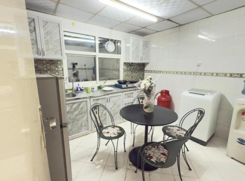 a kitchen with a table and chairs and a refrigerator at Stay home in ‘Uqayr