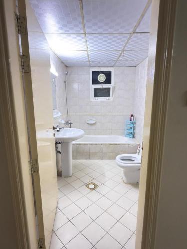 a bathroom with a toilet and a tub and a sink at Stay home in ‘Uqayr