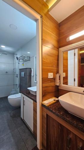 a bathroom with two sinks and a toilet and a mirror at S & B Dreams House in Munnar