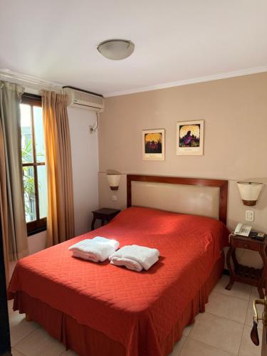 a bedroom with a red bed with two towels on it at Posada de Las Farolas in Salta
