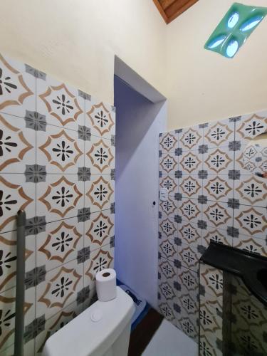 a bathroom with a toilet and tiles on the wall at Studio - Casa da Restinga in Cabo Frio