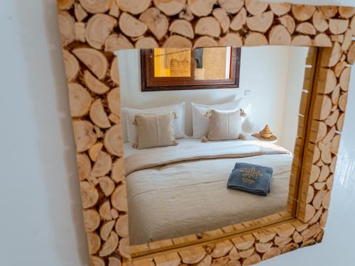 a mirror reflection of a bed in a room with wooden logs at Roots Surf House - Anza in Agadir