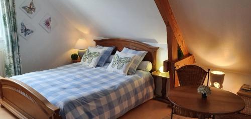 a bedroom with a bed with a blue and white checked blanket at Maison des Hortensias in Saint-Contest
