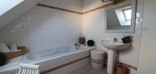 a white bathroom with a tub and a sink at Maison des Hortensias in Saint-Contest