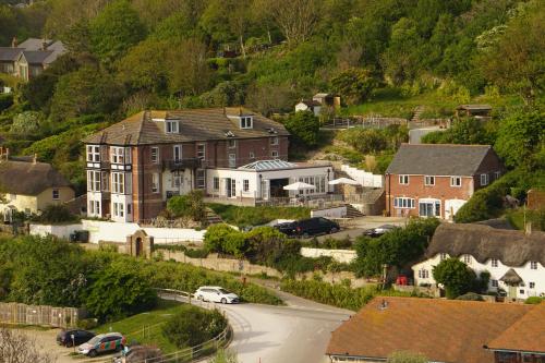 a house on a hill with cars parked in the street at Durdle Door Hotel in Lulworth Cove