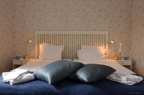a bed with two pillows on it with two lamps at Pensionat Prästgården in Töreboda