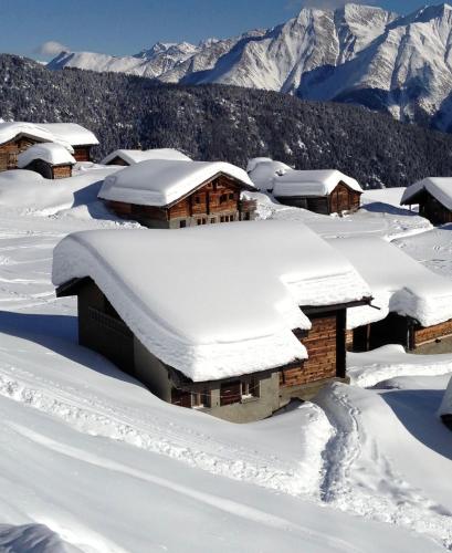 a snow covered cabin with mountains in the background at Chalet Abendruh Belalp in Naters