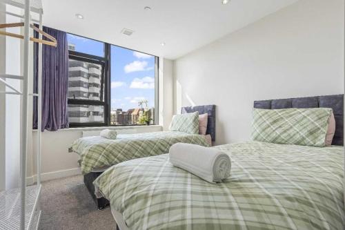 two beds in a room with a window at Heathrow Retail Park Aprt Sleeps SEVEN Turbo WiFi in Sunbury Common