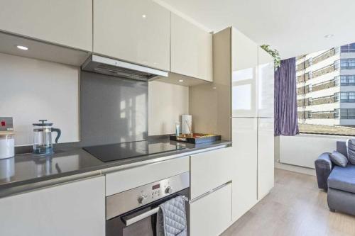 a kitchen with white cabinets and a stove top oven at Heathrow Retail Park Aprt Sleeps SEVEN Turbo WiFi in Sunbury Common