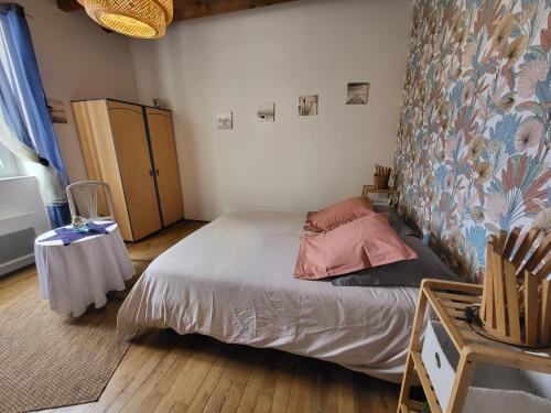 a small bedroom with a bed and a table at Au doux refuge in Saint-Exupéry-les-Roches