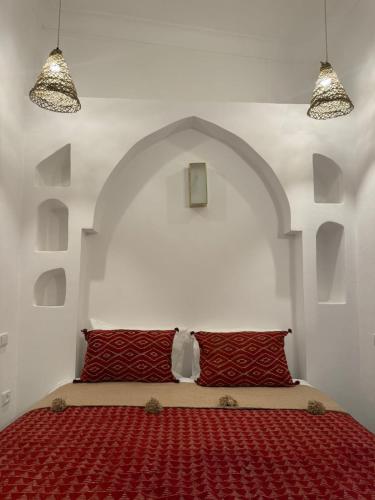 a bed with red pillows in a white room at Dar Raphael in Essaouira